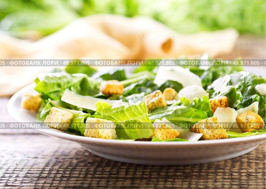 plate of caesar salad on wooden table. Стоковое фото, агентство Ingram Publishing / Фотобанк Лори