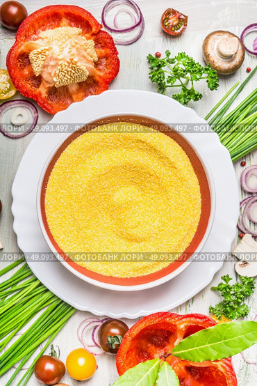 Polenta dish  and various vegetables and seasoning ingredients  for tasty vegetarian cooking on light  rustic wooden background, top view composing, close up. Healthy eating and diet food concept. Стоковое фото, агентство Ingram Publishing / Фотобанк Лори