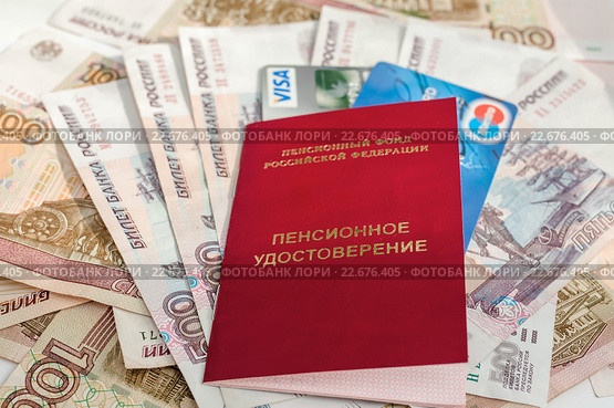 Получение пенсии. Удостоверение пенсионера и пластиковые карты лежат на бумажных банкнотах (2016 год). Редакционное фото, фотограф Игорь Низов / Фотобанк Лори