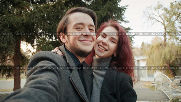 Portrait lovely young couple taking a selfie photo in the city park. Стоковое видео, видеограф EStarodubov / Фотобанк Лори