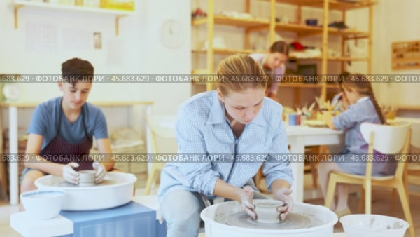 Portrait of a ceramics teacher with students and finished works after a master class. Teenage girl show clay products made themselves in the art studio. Стоковое видео, видеограф Яков Филимонов / Фотобанк Лори