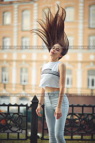 portrait of a girl in jeans and a t-shirt on the background of the building in the evening on a summer day. street dancing in the city. Стоковое фото, фотограф Арзюков Вадим Николаевич / Фотобанк Лори