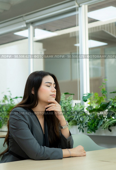 Portrait of a novice businesswoman in a new entrepreneurship. Closing his eyes to rest them in his office room. Стоковое фото, агентство Ingram Publishing / Фотобанк Лори