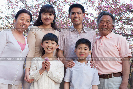 Portrait of a smiling multi-generational family amongst the cherry trees and enjoying the park in the springtime. Стоковое фото, агентство Ingram Publishing / Фотобанк Лори