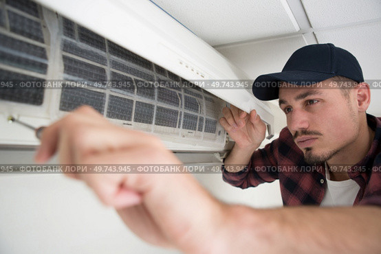 portrait of a young man adjusting air conditioning system. Стоковое фото, агентство Ingram Publishing / Фотобанк Лори