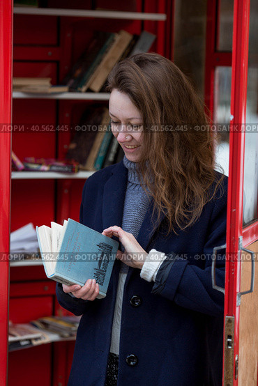 Portrait of a young woman over 30 years old with a book in her hands, a girl took a book from a street library. Modern lifestyle, reading books and education. Стоковое фото, фотограф Photojuli / Фотобанк Лори