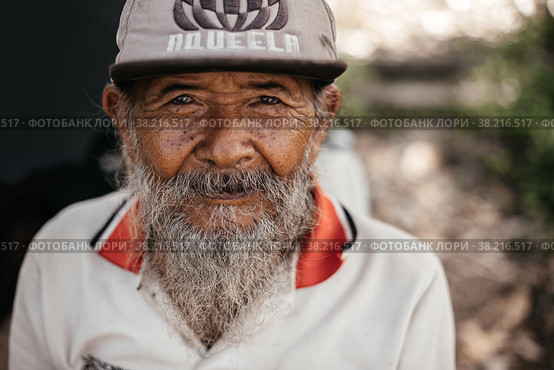 Portrait of an old Balinese man in an old sweater and cap. Indonesia, Bali, September 27, 2022. Редакционное фото, фотограф Евдокимов Максим / Фотобанк Лори