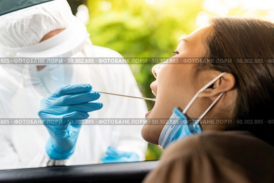 Portrait of asian woman drive thru coronavirus covid-19 test by medical staff with PPE suit by throat swab. New normal healthcare drive thru service and medical concept. Стоковое фото, агентство Ingram Publishing / Фотобанк Лори