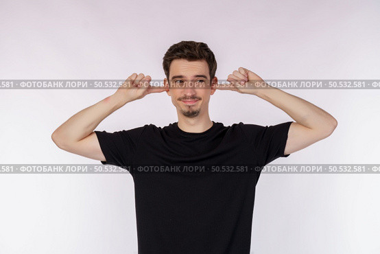 Portrait of attractive man close ears from noisy neighbours, looking up and shouting annoyed, hearing loud music on isolated background. . Стоковое фото, агентство Ingram Publishing / Фотобанк Лори