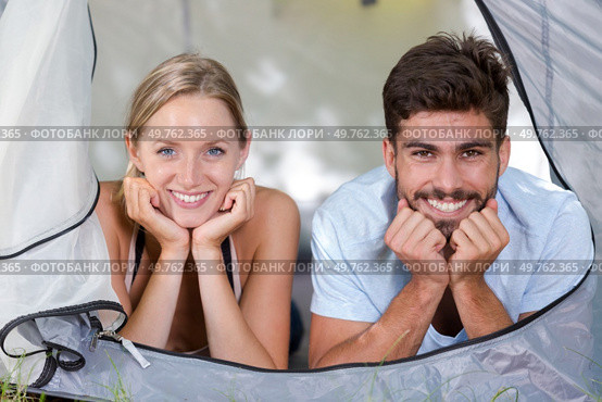 portrait of attractive young couple looking out from tent door. Стоковое фото, агентство Ingram Publishing / Фотобанк Лори