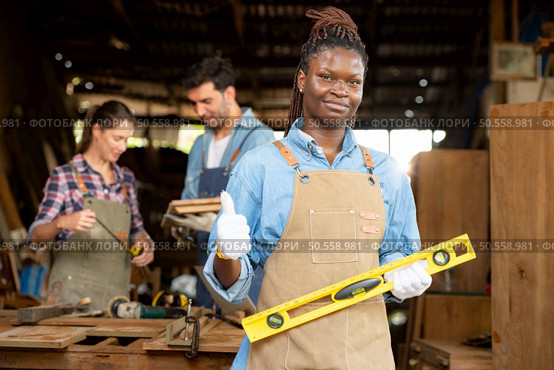 Portrait of carpenter female worker standing in front of colleague in workshop. Стоковое фото, агентство Ingram Publishing / Фотобанк Лори