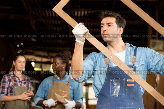 Portrait of carpenter male worker standing in front of colleague in workshop, Eyesight is utilized to ensure accuracy. Стоковое фото, агентство Ingram Publishing / Фотобанк Лори