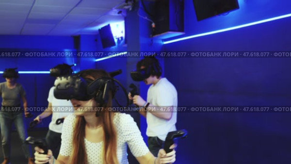 Portrait of happy excited young woman with VR glasses on head, holding handheld controllers playing virtual reality game with friends. Стоковое видео, видеограф Яков Филимонов / Фотобанк Лори