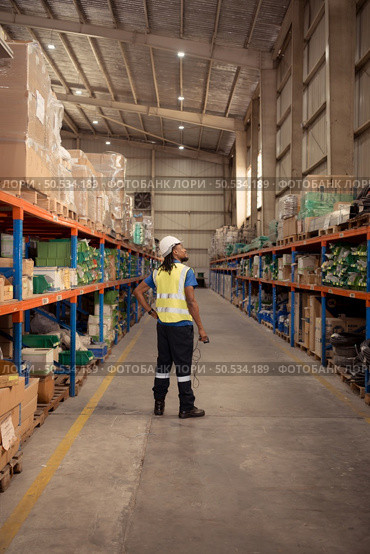 Portrait of male worker wearing hardhat and reflective vest holding hand scanner working in warehouse. Стоковое фото, агентство Ingram Publishing / Фотобанк Лори