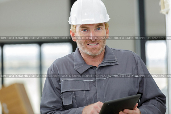 portrait of mature male worker wearing overalls holding digital tablet. Стоковое фото, агентство Ingram Publishing / Фотобанк Лори