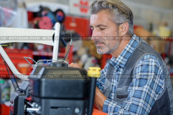 portrait of mechanic working on lawnmower. Стоковое фото, агентство Ingram Publishing / Фотобанк Лори