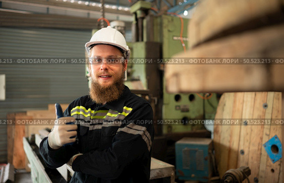 Portrait of mechanical engineers are checking the working condition of an old machine that has been used for some time. In a factory where natural light shines onto the workplace. Стоковое фото, агентство Ingram Publishing / Фотобанк Лори
