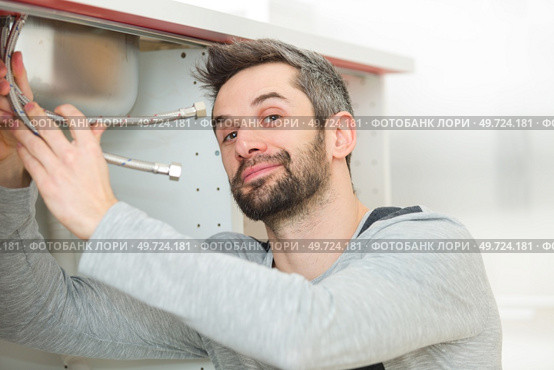 portrait of plumber fixing a sink. Стоковое фото, агентство Ingram Publishing / Фотобанк Лори