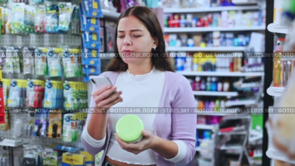 Portrait of smiling woman consumer choosing product at beauty shop, using smartphone for scanning barcode. Стоковое видео, видеограф Яков Филимонов / Фотобанк Лори