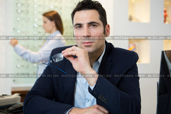 portrait of suited man holding eyeglasses in the opticians. Стоковое фото, агентство Ingram Publishing / Фотобанк Лори