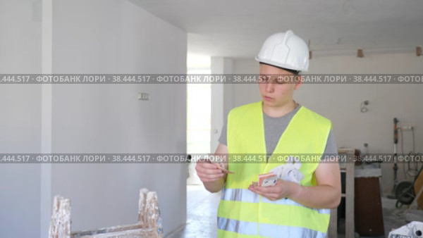 Portrait of teenage boy wearing yellow vest and hardhat holding bunch of earned money for part-time work in construction site. Стоковое видео, видеограф Яков Филимонов / Фотобанк Лори