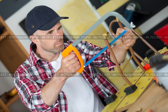 portrait of tradesman using hacksaw. Стоковое фото, агентство Ingram Publishing / Фотобанк Лори