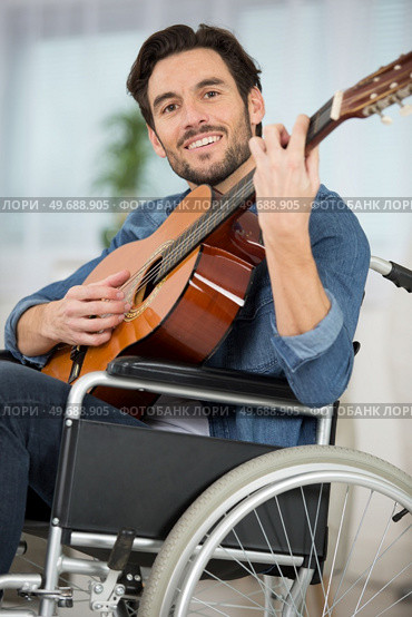 portrait of wheelchair bound man playing acoustic guitar. Стоковое фото, агентство Ingram Publishing / Фотобанк Лори