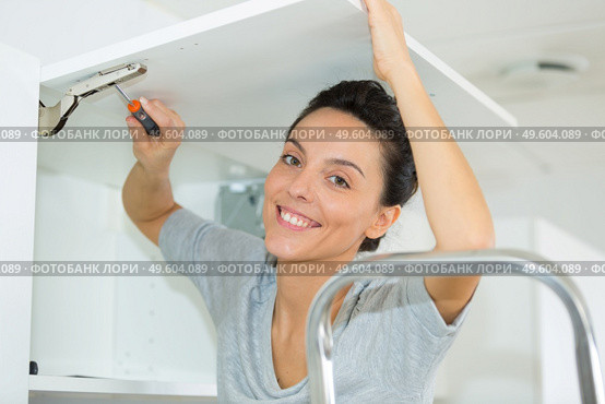 portrait of woman installing cupboard door. Стоковое фото, агентство Ingram Publishing / Фотобанк Лори