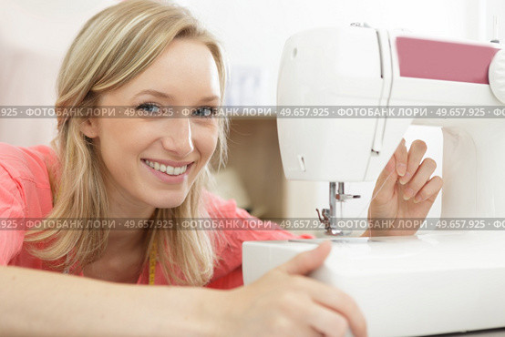 portrait of young woman threading sewing machine. Стоковое фото, агентство Ingram Publishing / Фотобанк Лори