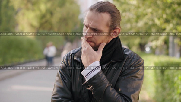 Портрет задумчивого человека, обдумывающего проблему. Portrait of a pensive man pondering a problem in a black jacket on a city street. Concept of people and emotions. Стоковое видео, видеограф EStarodubov / Фотобанк Лори