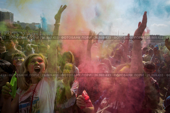 Посетители музыкального фестивале индийских красок ColorFest бросают друг друга сухой краской на конкурном стадионе в Битце города Москвы, Россия (2017 год). Редакционное фото, фотограф Николай Винокуров / Фотобанк Лори