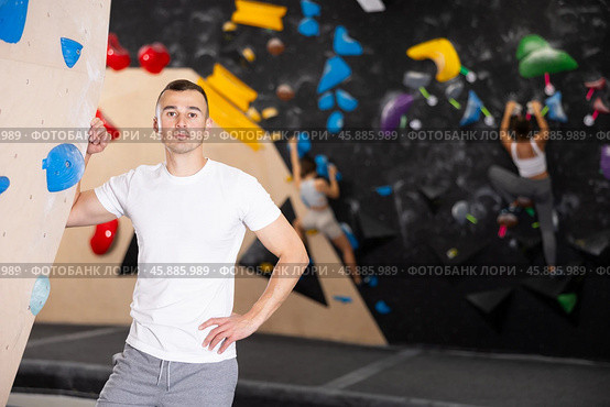 Positive European man in sportswear is standing near climbing wall in gym. Стоковое фото, фотограф Яков Филимонов / Фотобанк Лори