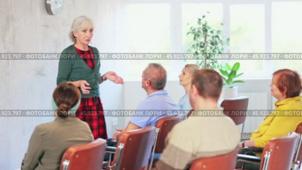 Positive friendly elderly woman giving lecture to group of older adults during educational class. Стоковое видео, видеограф Яков Филимонов / Фотобанк Лори