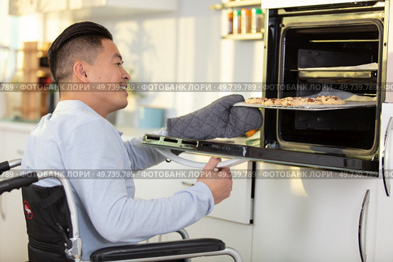 positive man in a wheelchair using the oven. Стоковое фото, агентство Ingram Publishing / Фотобанк Лори