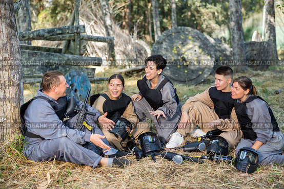Positive paintball players sitting on battleground and chatting. Стоковое фото, фотограф Яков Филимонов / Фотобанк Лори