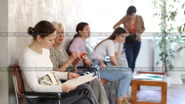 Positive woman sitting with papers in banking institution, waiting for meeting with financial advisor on loan issue. Стоковое видео, видеограф Яков Филимонов / Фотобанк Лори