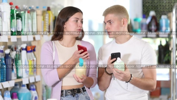 Positive young couple looking through barcode of liquid hand soap using smartphone while shopping. Стоковое видео, видеограф Яков Филимонов / Фотобанк Лори