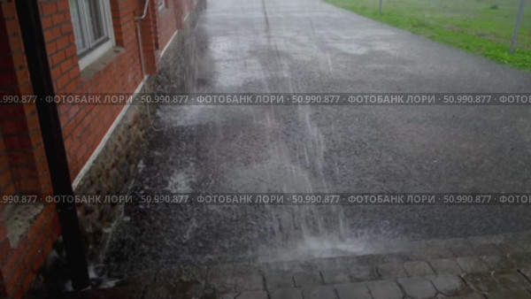 Потоки воды льются с крыши здания на мокрый асфальт, во время внезапного залпового ливня летом. Беларусь. Изменения климата. Стоковое видео, видеограф Sergei Gorin / Фотобанк Лори