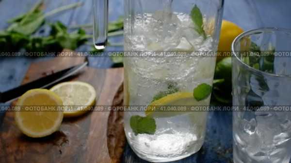 Pouring soda water from a decanter with ice lemon and mint. Making lemonade. Стоковое видео, видеограф Алексей Гекало / Фотобанк Лори