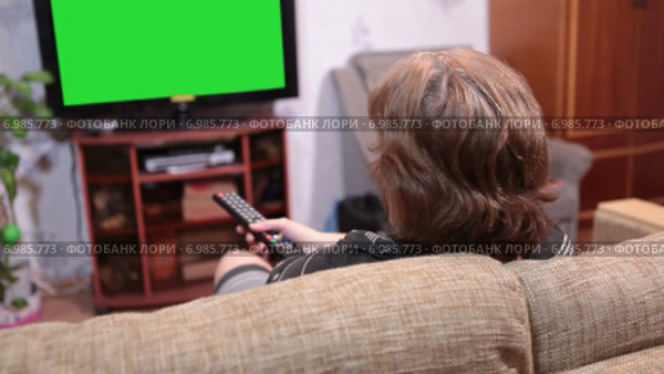 Пожилая женщина переключает каналы телевизора, зеленый экран, хромакей. Стоковое видео, видеограф Кекяляйнен Андрей / Фотобанк Лори