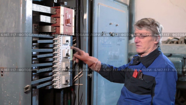Пожилой электрик рассказывает про тумблеры в шкафу управления, смотрит в камеру. Стоковое видео, видеограф Кекяляйнен Андрей / Фотобанк Лори