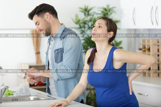 pregnant wife with back ache and husband in the kitchen. Стоковое фото, агентство Ingram Publishing / Фотобанк Лори