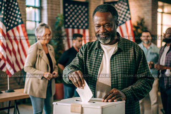 President elections. A black man votes for the new president of the United States of America and puts a form in the ballot box against the background of the American flag. Стоковое AI-изображение, AI-художник Photojuli / Фотобанк Лори