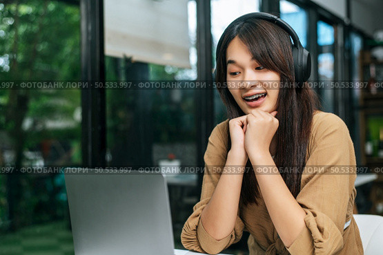 Pretty asian woman sitting and enjoy to listening musice from wireless headphone and singing together with smartphone at cafe, relaxing and lifestyle concept. Стоковое фото, агентство Ingram Publishing / Фотобанк Лори