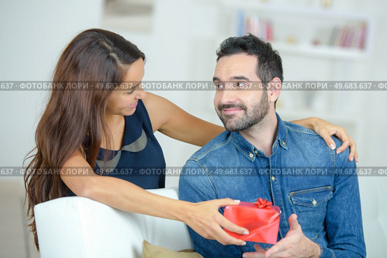pretty brunette surprising boyfriend with a gift at home. Стоковое фото, агентство Ingram Publishing / Фотобанк Лори