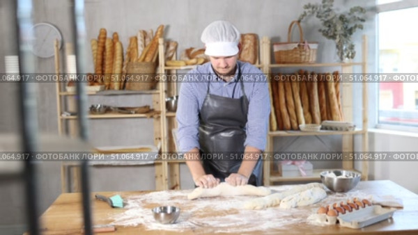 Process of making baguette, loaf or bread in bakery - baker kneads and rolls the dough to give the shape of the future bread. Стоковое видео, видеограф Яков Филимонов / Фотобанк Лори