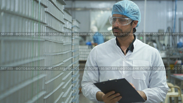 Production control supervisor inspects and controls the operation of each step in the production line of a canned fish factory. Стоковое фото, агентство Ingram Publishing / Фотобанк Лори