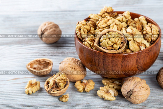 Purified walnuts in a brown wooden bowl on a wooden background. . Стоковое фото, агентство Ingram Publishing / Фотобанк Лори