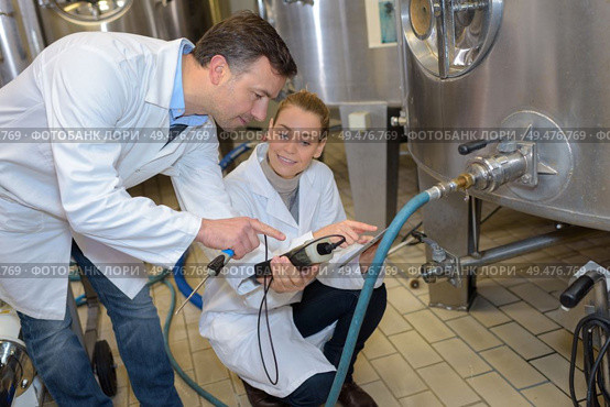 Quality controllers at stainless steel vat. Стоковое фото, агентство Ingram Publishing / Фотобанк Лори