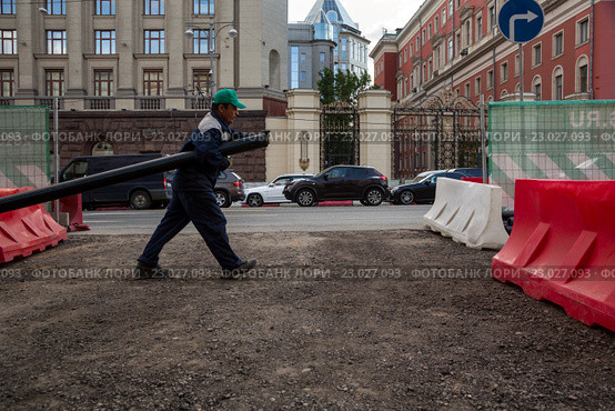 Рабочий прокладывает кабельную канализацию на Тверской улице города Москвы рядом со зданием мэрии города Москвы, Россия (2016 год). Редакционное фото, фотограф Николай Винокуров / Фотобанк Лори